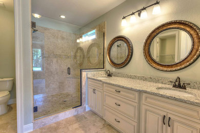 Example of a mid-sized classic master brown tile and ceramic tile ceramic tile and brown floor corner shower design in Miami with raised-panel cabinets, white cabinets, a one-piece toilet, gray walls, an undermount sink, granite countertops, a hinged shower door and gray countertops