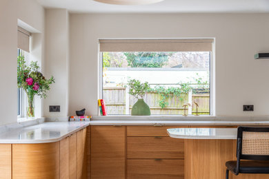 Large retro kitchen in London with medium wood cabinets, quartz worktops and an island.