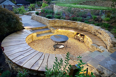 This is an example of a mid-sized country sloped full sun xeriscape for summer in Surrey with a fire feature and gravel.