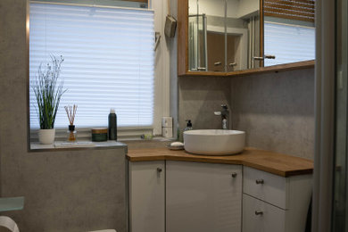 Kleines Modernes Duschbad mit flächenbündigen Schrankfronten, weißen Schränken, grauen Fliesen, grauer Wandfarbe, Vinylboden, Aufsatzwaschbecken, Waschtisch aus Holz, beiger Waschtischplatte, Einzelwaschbecken und freistehendem Waschtisch in Sonstige