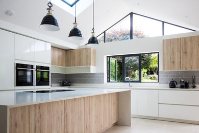 Inspiration for a large scandi l-shaped open plan kitchen in London with a built-in sink, glass-front cabinets, white cabinets, marble worktops, grey splashback, ceramic splashback, black appliances, ceramic flooring, an island, beige floors and white worktops.