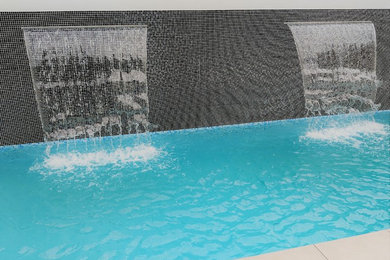 Mid-sized modern side yard rectangular pool in Adelaide with a water feature and tile.