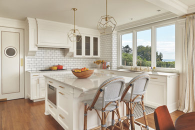 Eat-in kitchen - small transitional l-shaped medium tone wood floor eat-in kitchen idea in Seattle with an undermount sink, shaker cabinets, white cabinets, white backsplash, subway tile backsplash, white appliances and an island