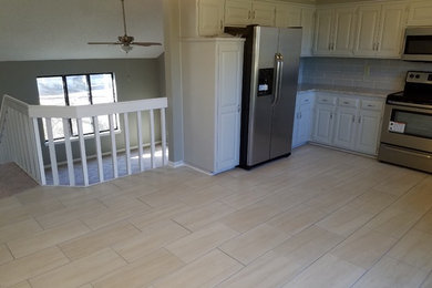 Example of a mid-sized classic u-shaped beige floor kitchen design in Kansas City with raised-panel cabinets, white cabinets, beige backsplash, subway tile backsplash, stainless steel appliances and a double-bowl sink