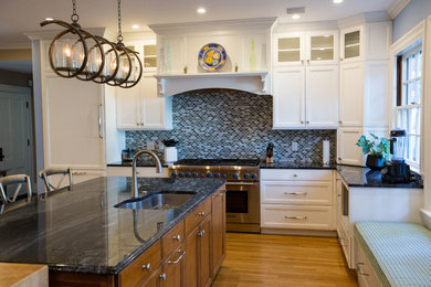 Inspiration for a large timeless l-shaped medium tone wood floor eat-in kitchen remodel in Boston with a drop-in sink, shaker cabinets, white cabinets, granite countertops, blue backsplash, mosaic tile backsplash, paneled appliances and an island