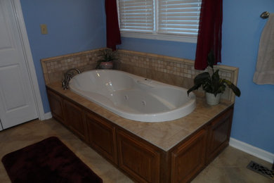 Inspiration for a small timeless master ceramic tile drop-in bathtub remodel in Other with blue walls, raised-panel cabinets, medium tone wood cabinets and granite countertops