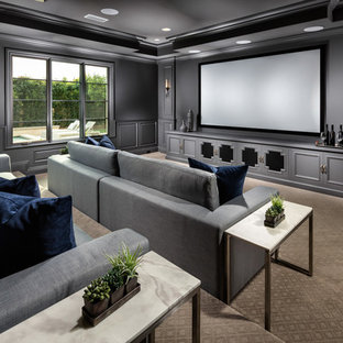 Classic enclosed home cinema in Los Angeles with grey walls, carpet, a projector screen and beige floors.