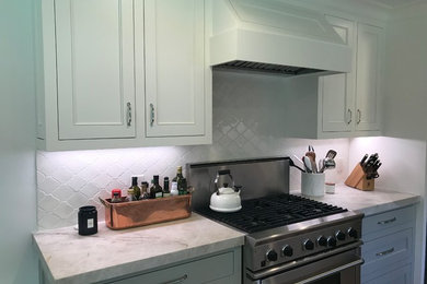 Example of a classic galley medium tone wood floor and brown floor kitchen design in Houston with a farmhouse sink, quartzite countertops, white backsplash, ceramic backsplash, stainless steel appliances, no island and white countertops