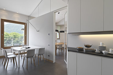 Design ideas for a large contemporary u-shaped separate kitchen in Turin with a drop-in sink, flat-panel cabinets, white cabinets, marble benchtops, white splashback, glass sheet splashback, stainless steel appliances, no island, ceramic floors and grey floor.