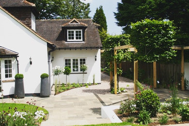 Photo of a large classic formal full sun garden in Surrey with a retaining wall and natural stone paving.