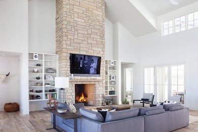 Design ideas for a large transitional living room in Denver with white walls, a standard fireplace, a stone fireplace surround, a wall-mounted tv, grey floor and medium hardwood floors.