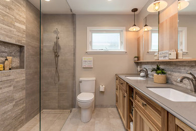 Inspiration for a mid-sized transitional 3/4 bathroom in San Francisco with recessed-panel cabinets, light wood cabinets, a corner shower, a two-piece toilet, brown tile, stone tile, beige walls, ceramic floors, an undermount sink, engineered quartz benchtops, beige floor, an open shower and grey benchtops.