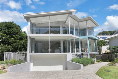 Design ideas for a mid-sized beach style three-storey exterior in Brisbane with a flat roof.