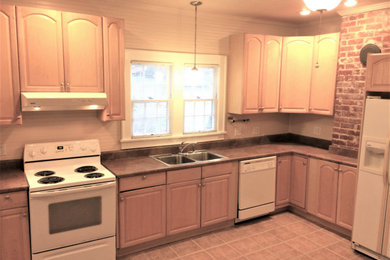 Example of an arts and crafts vinyl floor, brown floor and shiplap ceiling kitchen design with a double-bowl sink, shaker cabinets, white cabinets, granite countertops, white appliances and no island