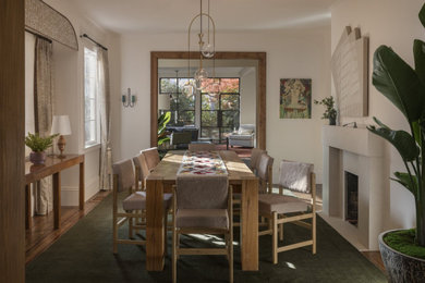 Exemple d'une salle à manger tendance fermée et de taille moyenne avec un mur jaune, un sol en bois brun, une cheminée standard, un manteau de cheminée en pierre et un sol vert.