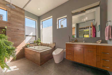 Photo of a mid-sized contemporary master bathroom in San Francisco with medium wood cabinets, a drop-in tub, a curbless shower, grey walls, porcelain floors, grey floor and a shower curtain.