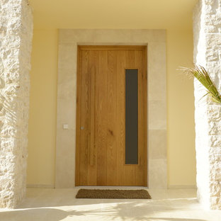 Inspiration for a mid-sized mediterranean limestone floor and beige floor entryway remodel in Munich with a medium wood front door and yellow walls