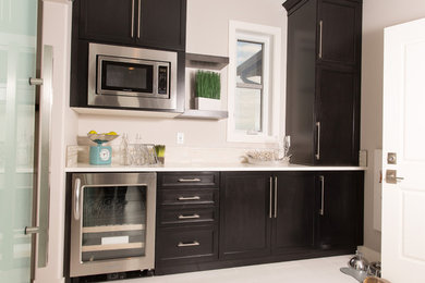 Inspiration for a modern single-wall ceramic tile kitchen pantry remodel in Calgary with recessed-panel cabinets, dark wood cabinets, quartzite countertops, white backsplash, glass tile backsplash and stainless steel appliances