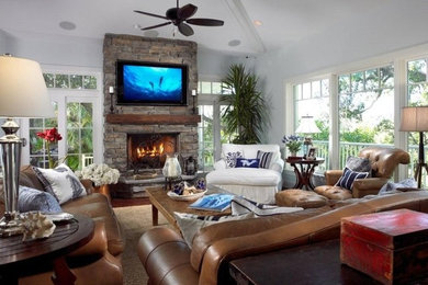 Inspiration for a large coastal open concept dark wood floor and brown floor family room remodel in Miami with gray walls, a standard fireplace, a stone fireplace and a wall-mounted tv