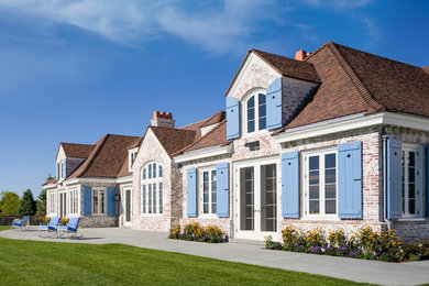 Inspiration for a huge timeless white one-story brick house exterior remodel in Providence with a tile roof