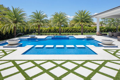 Inspiration for a large modern backyard custom-shaped lap pool in Miami with a hot tub.