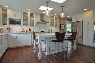 Example of a transitional u-shaped medium tone wood floor eat-in kitchen design in Cincinnati with an undermount sink, recessed-panel cabinets, white cabinets, white backsplash, subway tile backsplash, stainless steel appliances, an island and white countertops