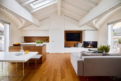 Idee per un soggiorno design con pavimento in legno verniciato, camino ad angolo, travi a vista, boiserie e TV a parete