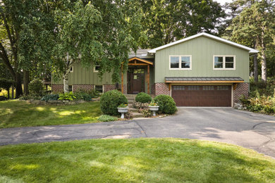 Mid-sized arts and crafts green split-level mixed siding and board and batten exterior home photo in Minneapolis with a mixed material roof and a brown roof