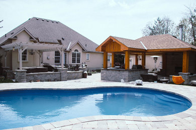 Inspiration for a large transitional backyard stone patio kitchen remodel in Toronto with a gazebo