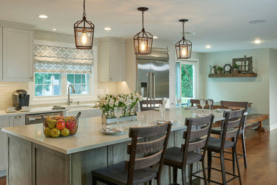 Example of a large transitional l-shaped medium tone wood floor eat-in kitchen design in Boston with a farmhouse sink, flat-panel cabinets, gray cabinets, quartz countertops, gray backsplash, glass tile backsplash, stainless steel appliances and an island