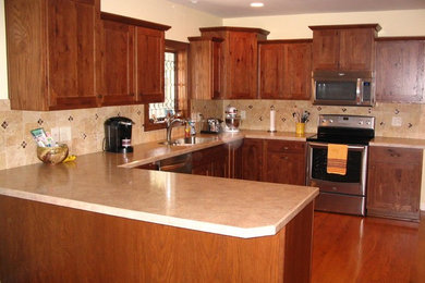 Eat-in kitchen - u-shaped medium tone wood floor eat-in kitchen idea in Other with a drop-in sink, recessed-panel cabinets, medium tone wood cabinets, solid surface countertops, beige backsplash, ceramic backsplash, stainless steel appliances and no island