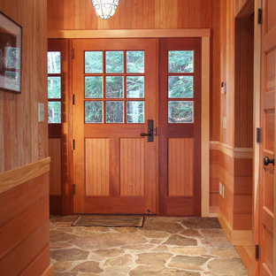 ボストンの大きい片開きドアラスティックスタイルのおしゃれな玄関ドア (木目調のドア、茶色い壁、ライムストーンの床、グレーの床) の写真