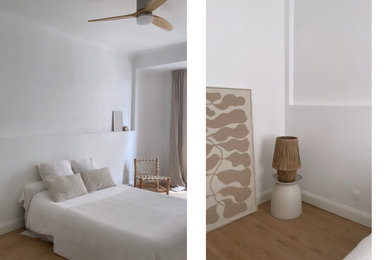 Cette photo montre une chambre d'amis blanche et bois tendance de taille moyenne avec un mur blanc, sol en stratifié, une cheminée standard, un manteau de cheminée en pierre, un sol marron et un plafond voûté.