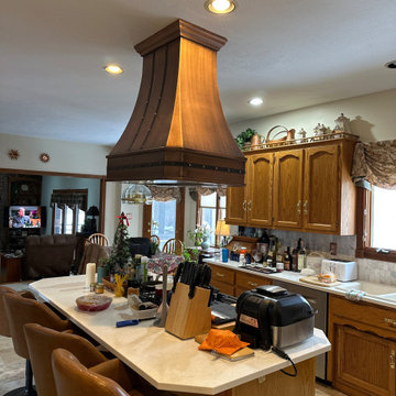 Dramatic Copper Range Hood Anchoring a Traditional Island Kitchen