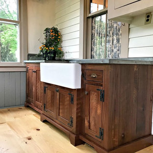 Design ideas for a medium sized country utility room in Philadelphia with a belfast sink, shaker cabinets, dark wood cabinets, zinc worktops, beige walls, light hardwood flooring, brown floors and grey worktops.
