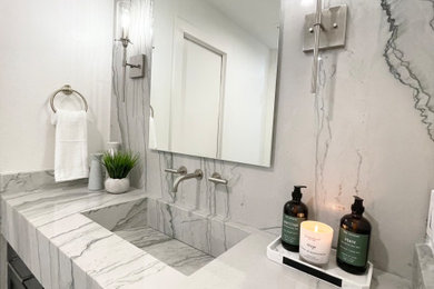 Inspiration for a mid-sized transitional stone slab ceramic tile, gray floor and single-sink bathroom remodel in Dallas with shaker cabinets, gray cabinets, white walls, an integrated sink, gray countertops, a niche and a built-in vanity