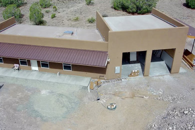 Mid-sized modern brown one-story stucco exterior home idea in Other with a brown roof
