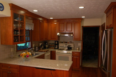 Example of a small classic u-shaped medium tone wood floor eat-in kitchen design in Columbus with an undermount sink, raised-panel cabinets, medium tone wood cabinets, quartz countertops, gray backsplash, subway tile backsplash, stainless steel appliances and a peninsula