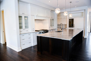 Example of a large trendy l-shaped dark wood floor and brown floor open concept kitchen design in Edmonton with a double-bowl sink, shaker cabinets, white cabinets, marble countertops, stainless steel appliances, an island, white backsplash and glass tile backsplash
