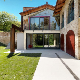 Exempel på ett stort lantligt brunt hus, med två våningar, tegel och sadeltak