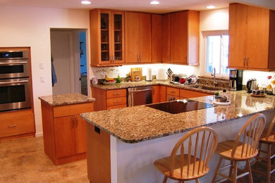 Trendy porcelain tile kitchen photo in Tampa with an undermount sink, flat-panel cabinets, medium tone wood cabinets, granite countertops and stainless steel appliances