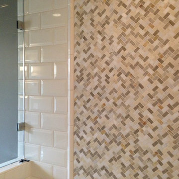 Herringbone marble array with beveled ceramic tile in main level bath