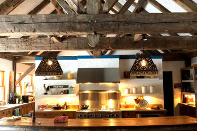 Huge southwest single-wall brick floor and red floor eat-in kitchen photo in Other with beaded inset cabinets, distressed cabinets, wood countertops, metal backsplash, an island and brown countertops