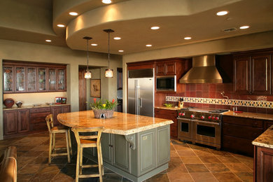 Huge transitional l-shaped slate floor eat-in kitchen photo in Phoenix with a farmhouse sink, raised-panel cabinets, dark wood cabinets, granite countertops, mosaic tile backsplash, stainless steel appliances and an island