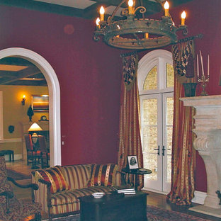 Großes, Repräsentatives Mediterranes Wohnzimmer mit roter Wandfarbe, braunem Holzboden und Kaminsims aus Stein in Raleigh