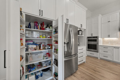 Kitchen pantry - large transitional vinyl floor and brown floor kitchen pantry idea in Dallas with an undermount sink, shaker cabinets, white cabinets, quartz countertops, beige backsplash, subway tile backsplash, stainless steel appliances, an island and white countertops