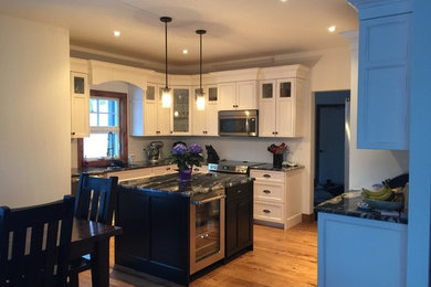 Inspiration for a mid-sized l-shaped kitchen remodel in Toronto with an undermount sink, distressed cabinets, granite countertops, white backsplash, stainless steel appliances and an island