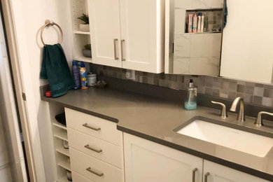 Inspiration for a small transitional white tile and ceramic tile vinyl floor, gray floor and single-sink alcove shower remodel in Other with shaker cabinets, white cabinets, a two-piece toilet, gray walls, an undermount sink, quartz countertops, a hinged shower door, gray countertops, a niche and a built-in vanity