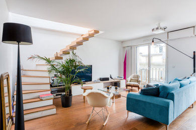 Idée de décoration pour une grande salle de séjour design ouverte avec un mur blanc, parquet clair, aucune cheminée, un téléviseur indépendant et un sol marron.