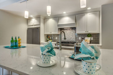 Large transitional single-wall medium tone wood floor and brown floor eat-in kitchen photo in Boston with an undermount sink, flat-panel cabinets, white cabinets, quartz countertops, gray backsplash, ceramic backsplash, stainless steel appliances and an island